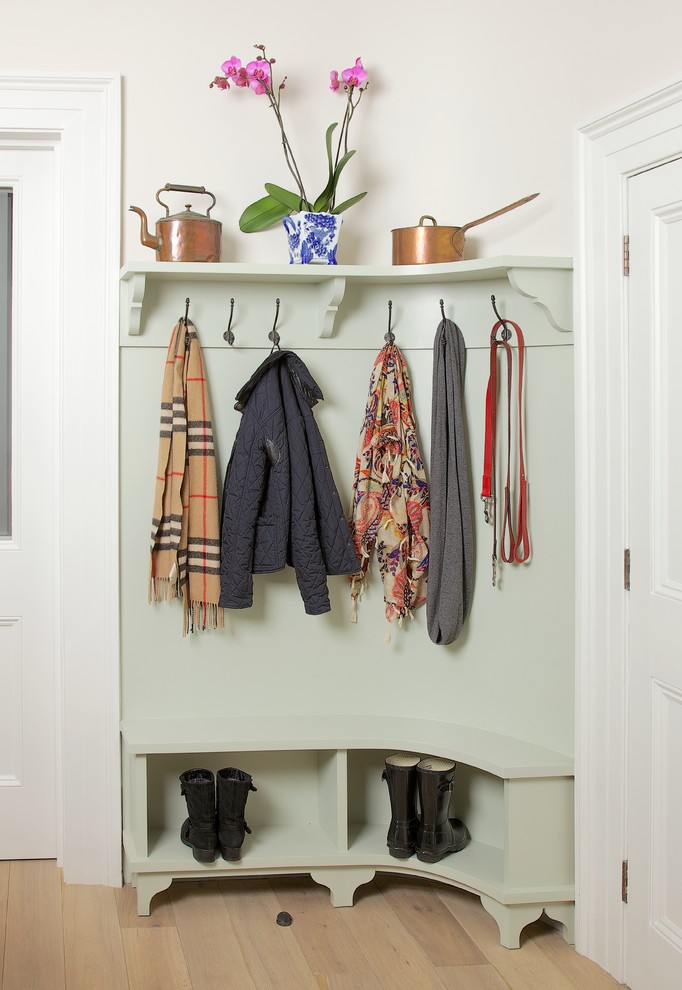 This is an example of a small traditional mudroom in Surrey with green walls, light hardwood floors and a single front door.