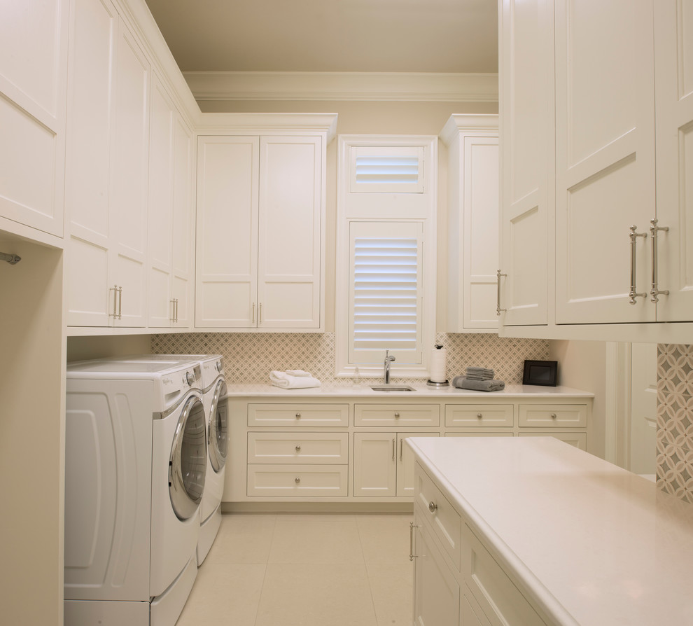 This is an example of a large transitional laundry room in Houston with white cabinets and a side-by-side washer and dryer.