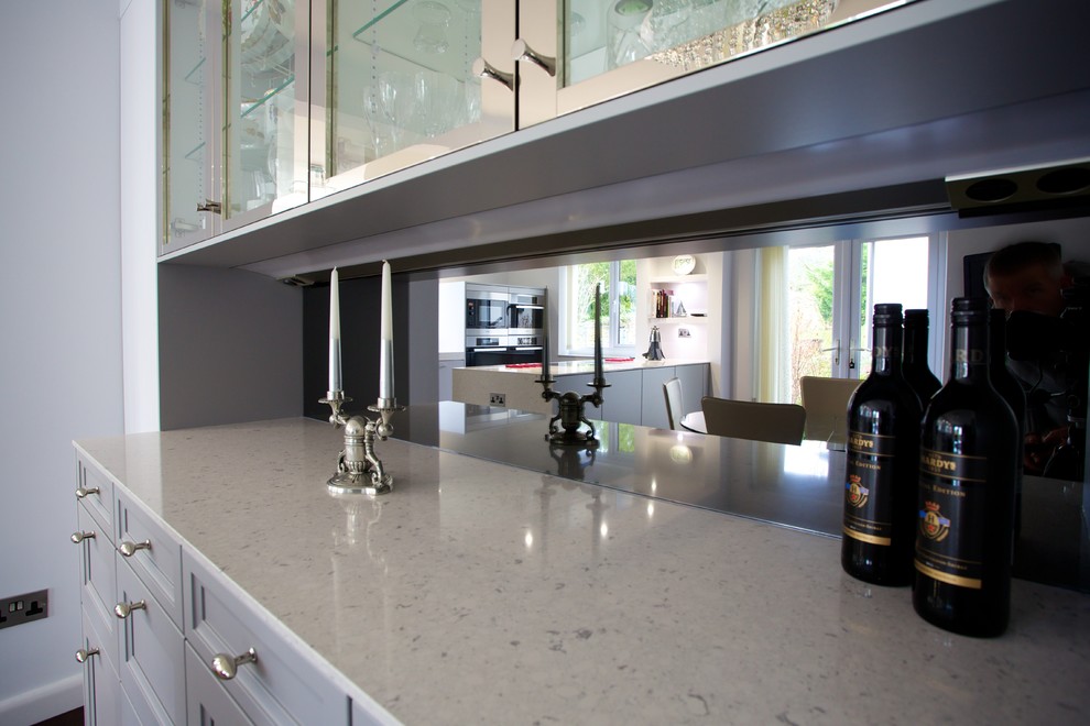 Inspiration for a small contemporary galley eat-in kitchen in Hampshire with an undermount sink, flat-panel cabinets, grey cabinets, solid surface benchtops, grey splashback, stainless steel appliances and with island.