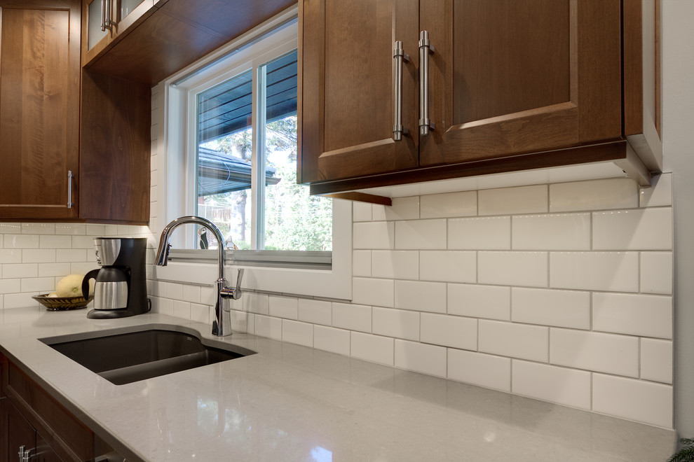Inspiration for a mid-sized transitional u-shaped kitchen pantry remodel with an undermount sink, shaker cabinets, medium tone wood cabinets, solid surface countertops, white backsplash, subway tile backsplash, stainless steel appliances and an island