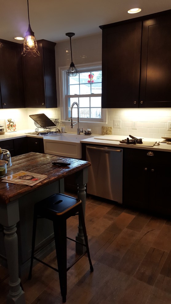 Inspiration for a mid-sized rustic u-shaped porcelain tile eat-in kitchen remodel in Indianapolis with a farmhouse sink, shaker cabinets, dark wood cabinets, wood countertops, white backsplash, ceramic backsplash, stainless steel appliances and an island