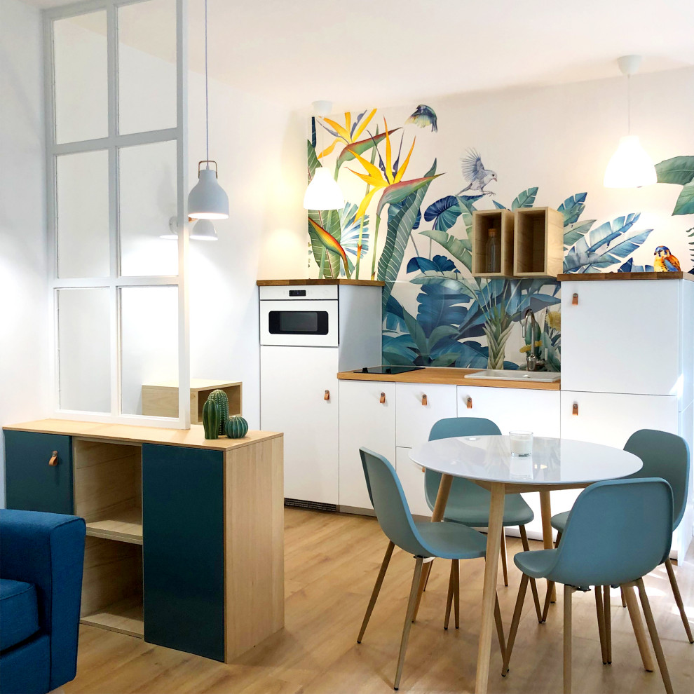 This is an example of a mid-sized contemporary single-wall open plan kitchen in Paris with a drop-in sink, flat-panel cabinets, white cabinets, wood benchtops, panelled appliances, medium hardwood floors, no island, beige floor and beige benchtop.