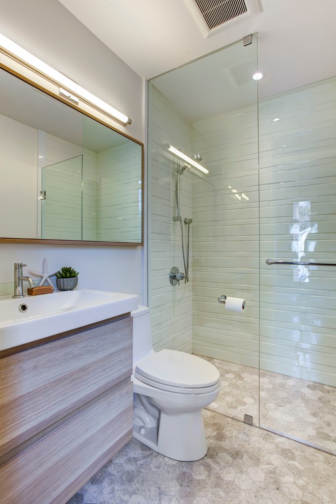 Small transitional 3/4 bathroom in Toronto with a console sink, flat-panel cabinets, light wood cabinets, a curbless shower, a one-piece toilet, white tile, porcelain tile, white walls, limestone floors and solid surface benchtops.