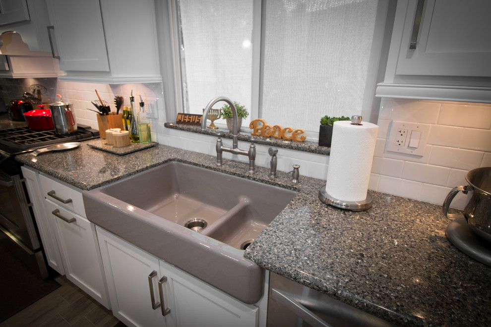 Open concept kitchen - mid-sized transitional galley porcelain tile open concept kitchen idea with a farmhouse sink, shaker cabinets, white cabinets, quartz countertops, white backsplash, subway tile backsplash and stainless steel appliances