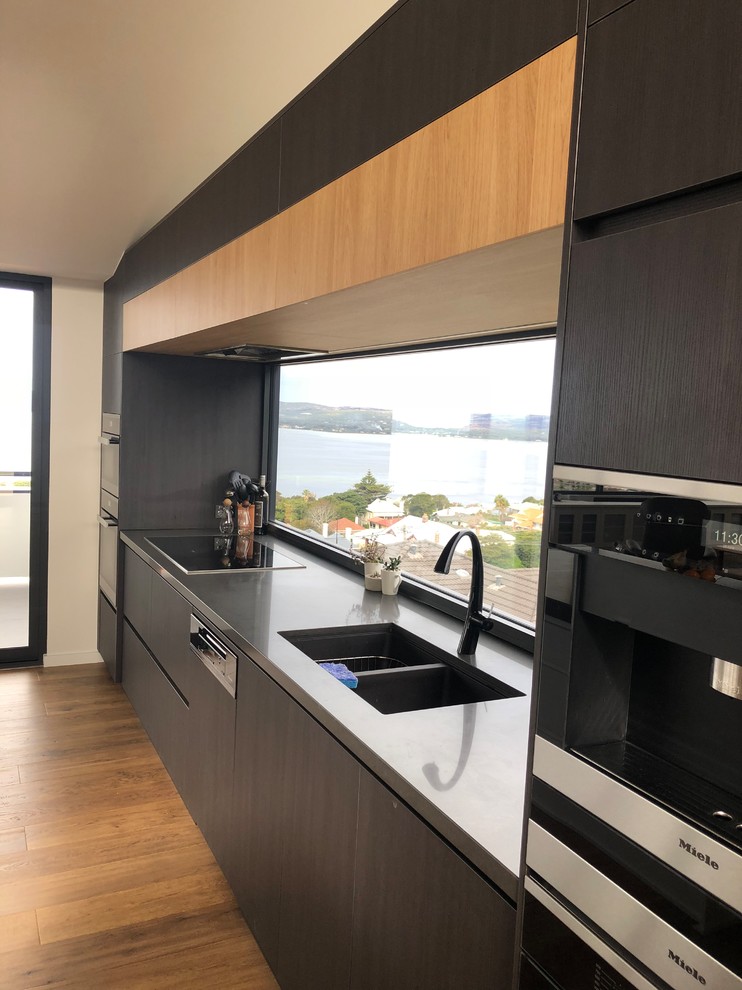 Design ideas for a large modern galley kitchen in Other with an undermount sink, flat-panel cabinets, dark wood cabinets, quartz benchtops, window splashback, stainless steel appliances, with island and black benchtop.