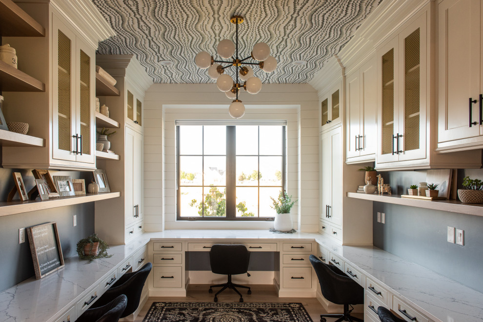Photo of a transitional home office in Salt Lake City with white walls, light hardwood floors, a built-in desk, beige floor and wallpaper.