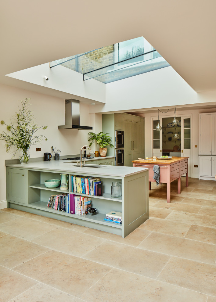 Large transitional l-shaped eat-in kitchen in London with an integrated sink, recessed-panel cabinets, marble benchtops, panelled appliances, limestone floors, with island, beige floor and white benchtop.