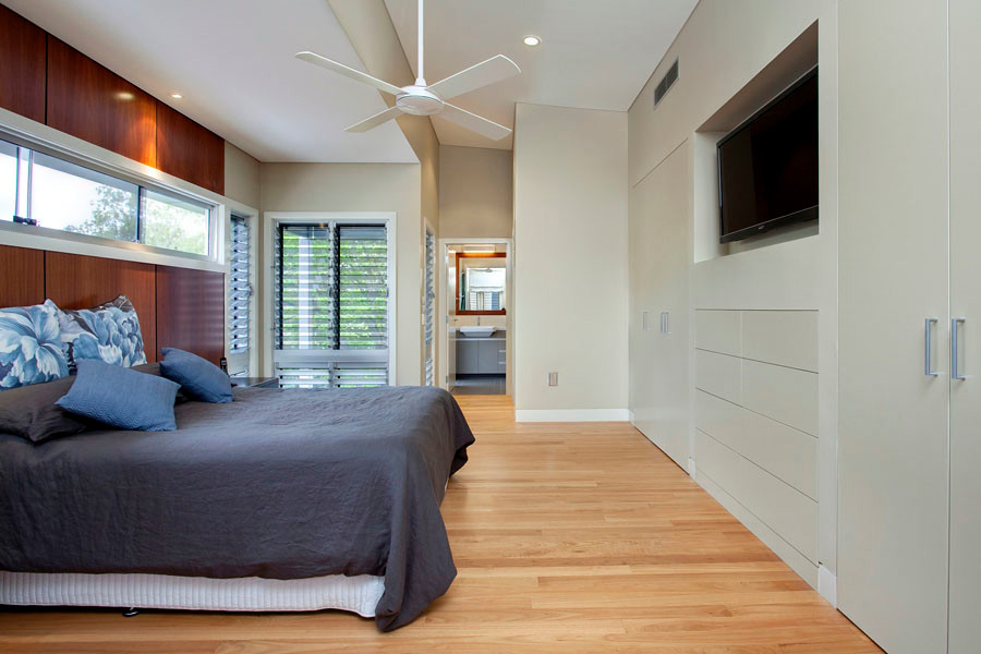 Expansive contemporary master bedroom in Brisbane with beige walls, light hardwood floors, no fireplace and brown floor.