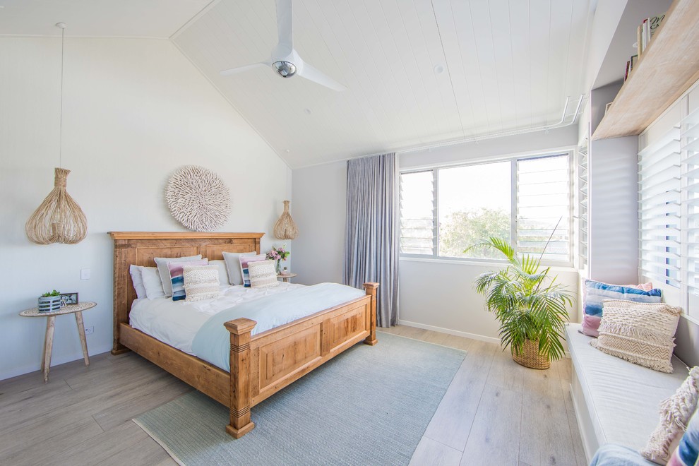 Design ideas for a large beach style master bedroom in Gold Coast - Tweed with white walls, light hardwood floors and grey floor.
