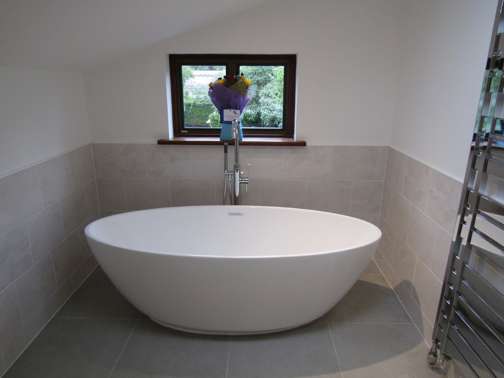 Contemporary kids bathroom in Hampshire with a freestanding tub, a shower/bathtub combo, gray tile, ceramic tile, ceramic floors and grey floor.