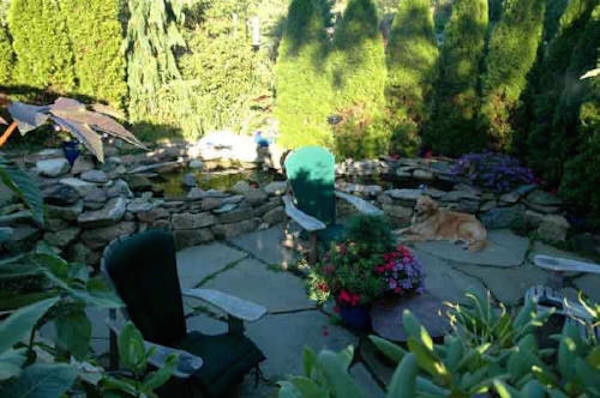 This is an example of a mid-sized tropical backyard partial sun formal garden for summer in Portland Maine with a water feature and natural stone pavers.