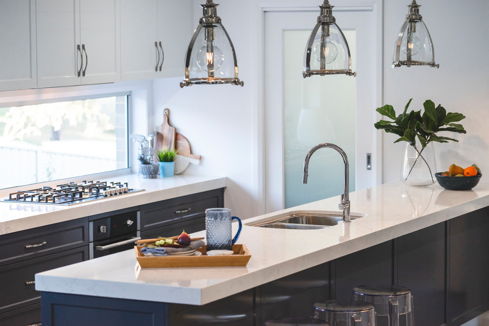 Inspiration for a contemporary galley kitchen pantry in Other with an undermount sink, shaker cabinets, blue cabinets, quartz benchtops, window splashback, black appliances, with island and white benchtop.