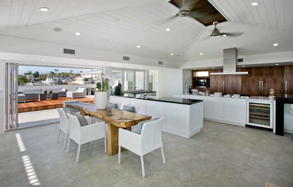 Large transitional u-shaped open plan kitchen in Los Angeles with a farmhouse sink, flat-panel cabinets, medium wood cabinets, quartzite benchtops, stainless steel appliances, limestone floors and multiple islands.