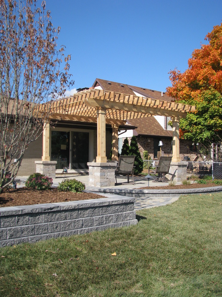 Photo of a backyard patio in Detroit with an outdoor kitchen, brick pavers and a pergola.