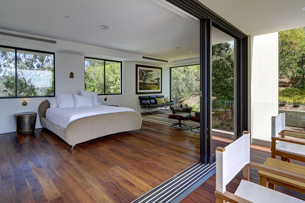 This is an example of a modern bedroom in Los Angeles with white walls, medium hardwood floors and no fireplace.