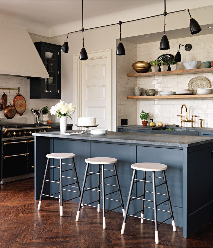 Inspiration for a mid-sized transitional u-shaped eat-in kitchen in New York with a farmhouse sink, shaker cabinets, blue cabinets, soapstone benchtops, white splashback, ceramic splashback, coloured appliances, medium hardwood floors, with island and brown floor.