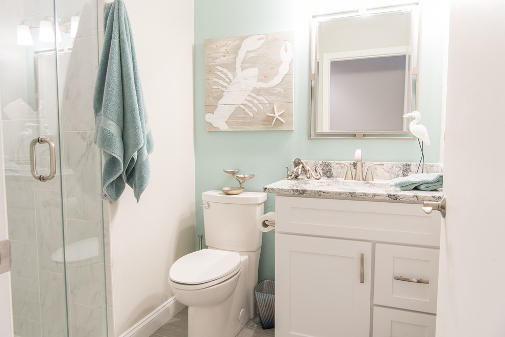 This is an example of a small beach style bathroom in Orlando with shaker cabinets, white cabinets, an alcove shower, a two-piece toilet, white tile, porcelain tile, blue walls, porcelain floors, an undermount sink and engineered quartz benchtops.