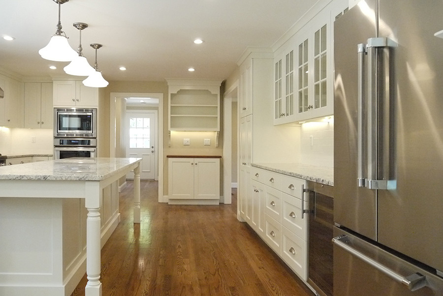 Inspiration for a large transitional u-shaped medium tone wood floor eat-in kitchen remodel in Boston with an undermount sink, shaker cabinets, white cabinets, granite countertops, white backsplash, ceramic backsplash, stainless steel appliances and an island