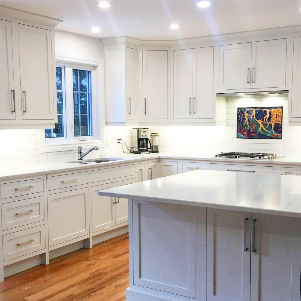 Eat-in kitchen - large transitional u-shaped light wood floor and beige floor eat-in kitchen idea with a double-bowl sink, shaker cabinets, white cabinets, quartzite countertops, white backsplash, subway tile backsplash, stainless steel appliances, an island and white countertops