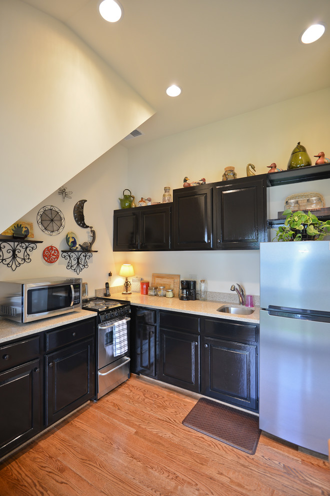 Small l-shaped medium tone wood floor open concept kitchen photo in DC Metro with an undermount sink, raised-panel cabinets, black cabinets, quartz countertops and stainless steel appliances