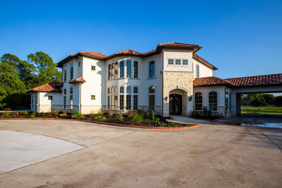 Expansive mediterranean two-storey stucco white house exterior in Dallas with a gable roof and a tile roof.