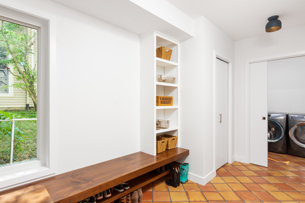 Design ideas for a modern mudroom in Detroit with white walls, terra-cotta floors and orange floor.