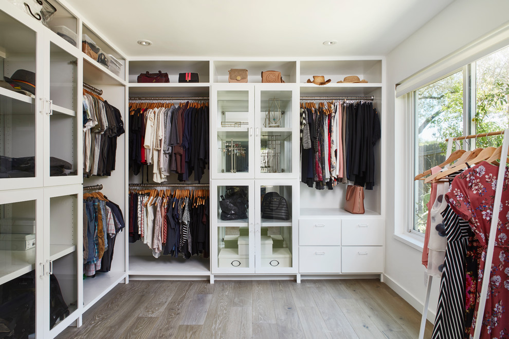 Photo of a transitional gender-neutral storage and wardrobe in Austin with white cabinets and beige floor.