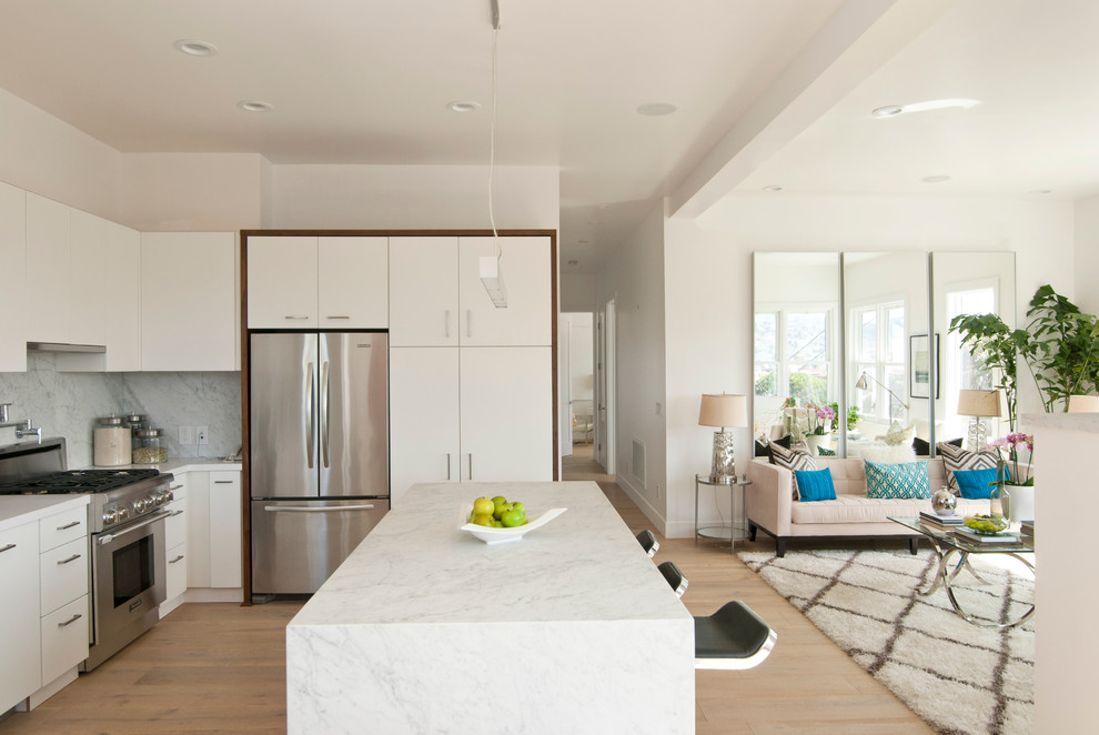 Photo of a scandinavian open plan kitchen in San Francisco with flat-panel cabinets, white cabinets, marble benchtops, white splashback, light hardwood floors, with island and marble splashback.