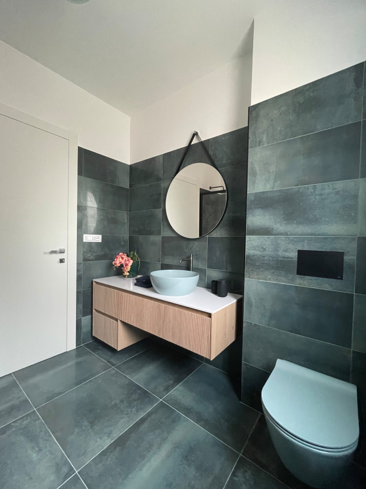 Photo of a large contemporary cloakroom in Rome with raised-panel cabinets, light wood cabinets, a wall mounted toilet, green tiles, porcelain tiles, porcelain flooring, a vessel sink, solid surface worktops, green floors, white worktops and a floating vanity unit.