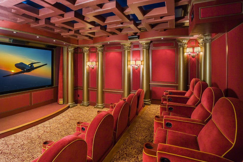 This is an example of a traditional enclosed home theatre in Boston with red walls, carpet and a projector screen.