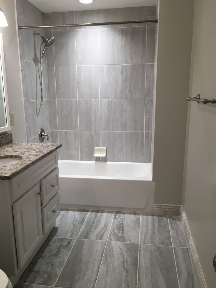 This is an example of a small transitional bathroom in Nashville with raised-panel cabinets, white cabinets, an alcove tub, a shower/bathtub combo, gray tile, porcelain tile, an undermount sink, granite benchtops, grey floor, a shower curtain and grey benchtops.