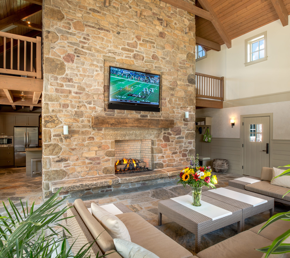 This is an example of a large traditional open concept living room in Philadelphia with a home bar, beige walls, travertine floors, a standard fireplace, a stone fireplace surround and a built-in media wall.