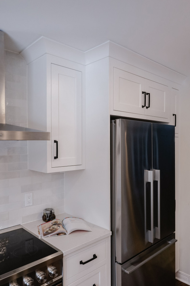 Eat-in kitchen - small transitional u-shaped medium tone wood floor and brown floor eat-in kitchen idea in Ottawa with an undermount sink, shaker cabinets, white cabinets, quartz countertops, white backsplash, subway tile backsplash, stainless steel appliances, an island and white countertops