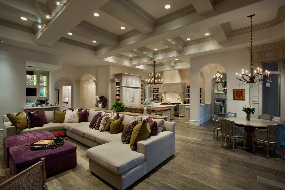 This is an example of an expansive traditional open concept living room in Phoenix with a home bar, beige walls, medium hardwood floors, a standard fireplace, a stone fireplace surround, a wall-mounted tv and brown floor.