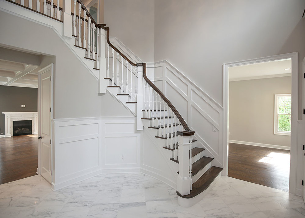This is an example of a large transitional foyer in New York with grey walls, marble floors, a double front door and a light wood front door.