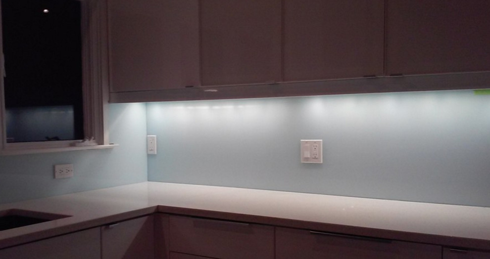 Contemporary kitchen in New York with blue splashback and glass tile splashback.