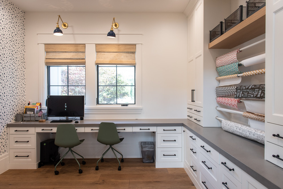 Photo of a country craft room in Salt Lake City with white walls, medium hardwood floors, a built-in desk and brown floor.