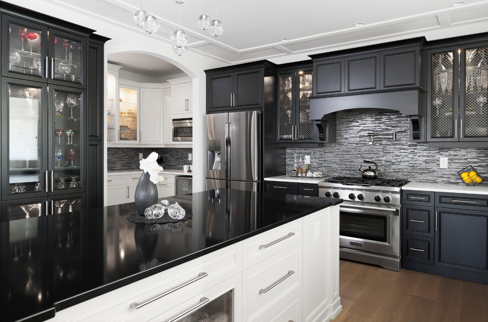 Kitchen pantry - large transitional l-shaped medium tone wood floor and brown floor kitchen pantry idea with an undermount sink, recessed-panel cabinets, black cabinets, quartz countertops, gray backsplash, glass tile backsplash, stainless steel appliances, an island and white countertops