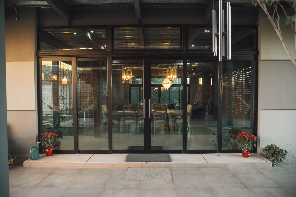 Large industrial entry hall in Other with grey walls, concrete floors, a metal front door, grey floor, a sliding front door and exposed beam.
