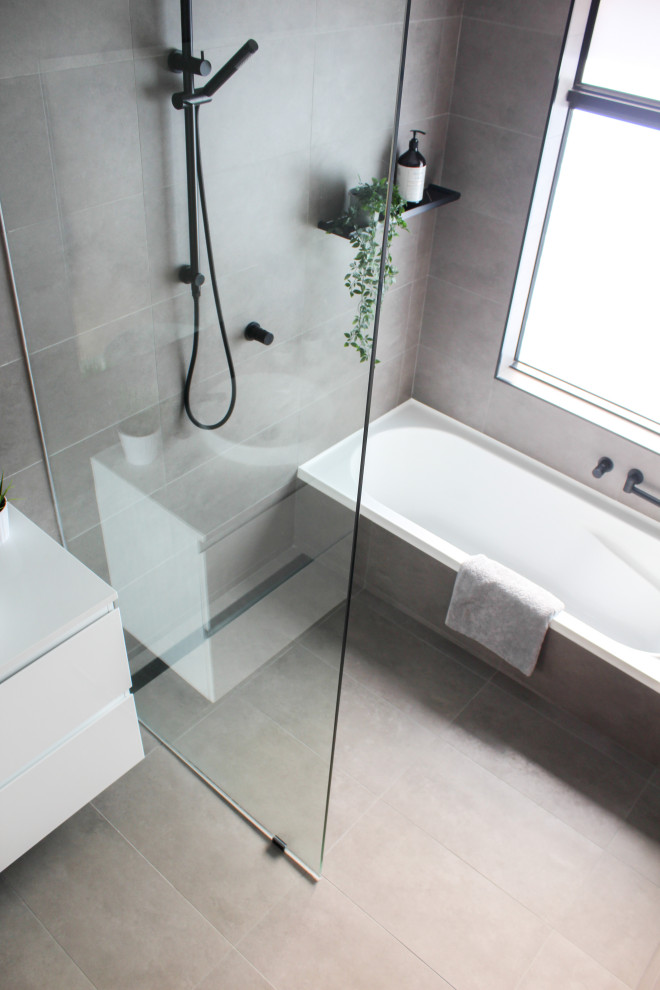 Photo of a mid-sized modern kids wet room bathroom in Perth with flat-panel cabinets, white cabinets, a drop-in tub, a one-piece toilet, gray tile, porcelain tile, grey walls, porcelain floors, a vessel sink, engineered quartz benchtops, grey floor, an open shower, white benchtops, a single vanity and a floating vanity.