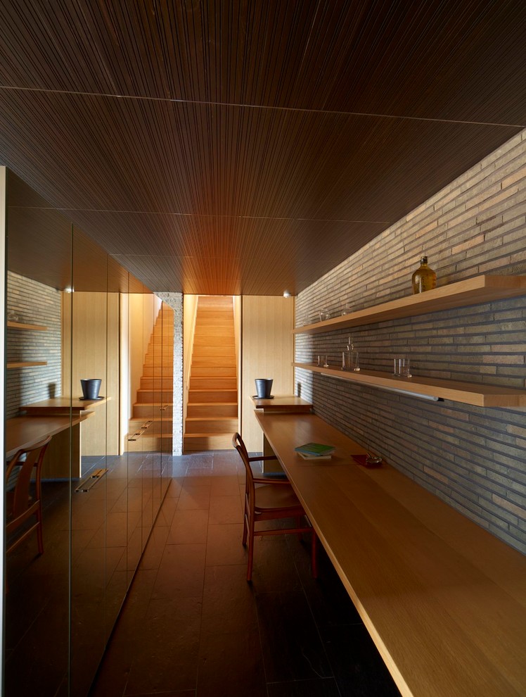 This is an example of an asian home office in Yokohama with grey walls, a built-in desk and brown floor.