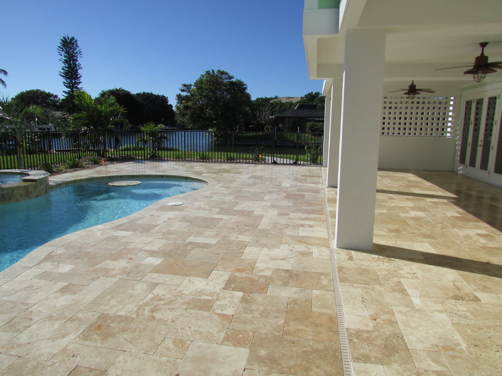 Design ideas for a large beach style backyard patio in Miami with tile and a roof extension.