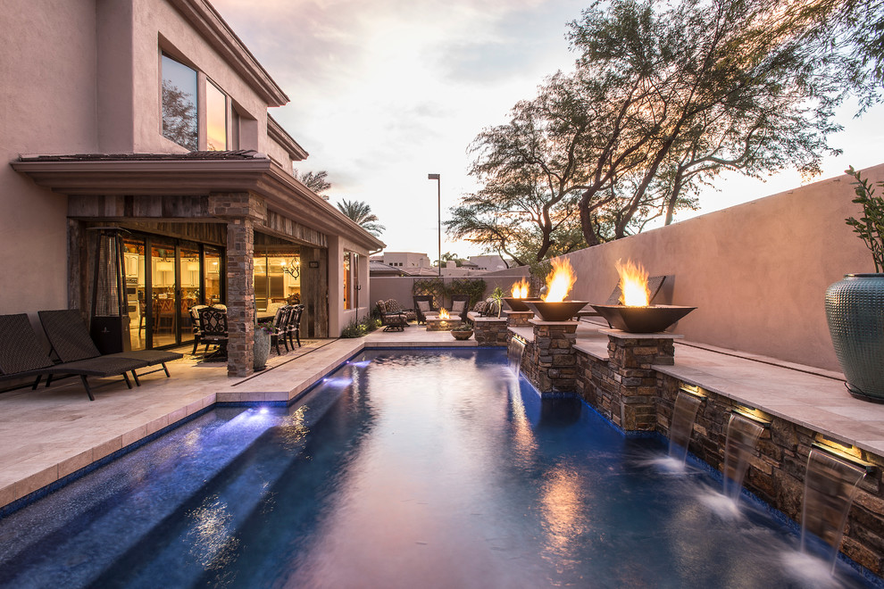 Design ideas for a mid-sized transitional backyard l-shaped pool in Phoenix with a water feature and natural stone pavers.