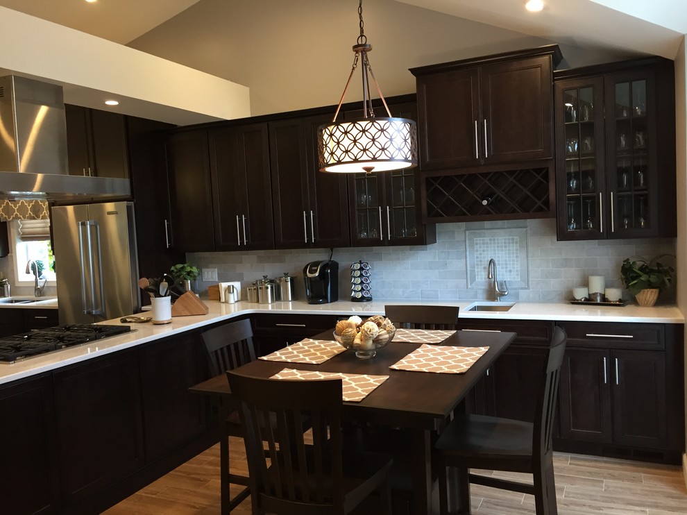 Large contemporary single-wall eat-in kitchen in Philadelphia with an undermount sink, recessed-panel cabinets, dark wood cabinets, quartz benchtops, grey splashback, subway tile splashback, stainless steel appliances, porcelain floors and multiple islands.