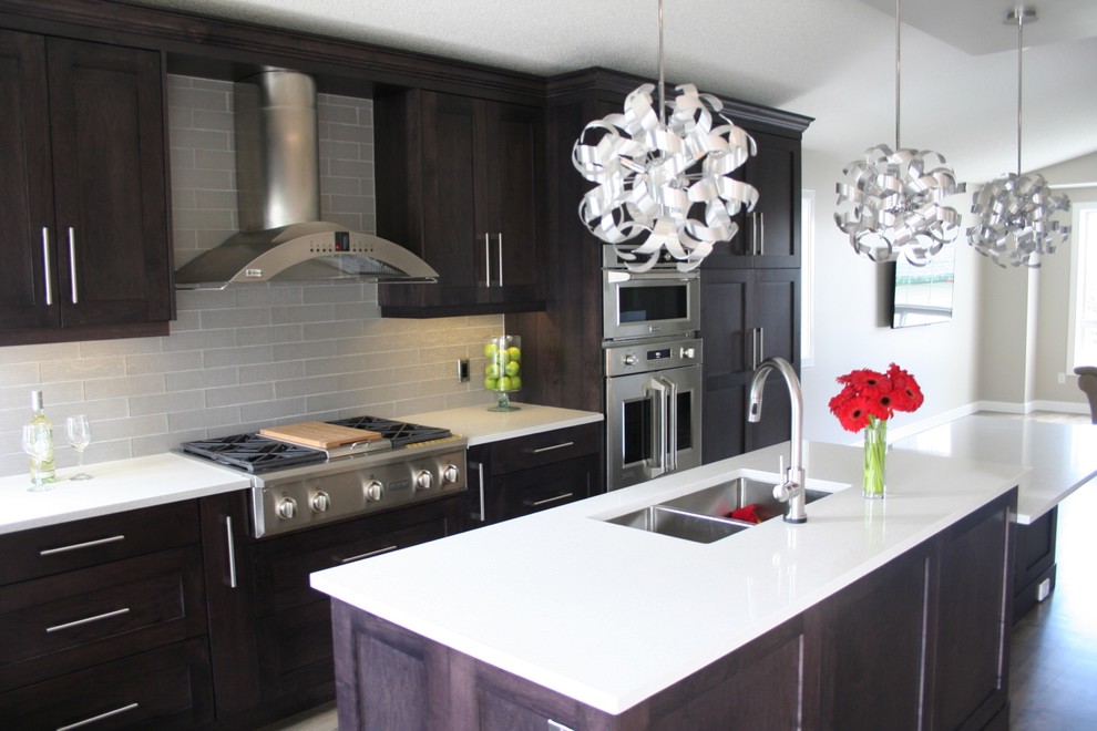 Mid-sized transitional l-shaped dark wood floor open concept kitchen photo in Calgary with a triple-bowl sink, shaker cabinets, dark wood cabinets, quartz countertops, gray backsplash, glass tile backsplash, stainless steel appliances and an island