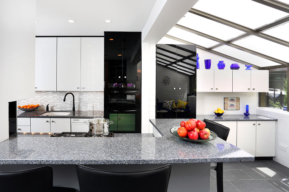 This is an example of a mid-sized contemporary galley eat-in kitchen in Chicago with an undermount sink, flat-panel cabinets, grey splashback, matchstick tile splashback, black appliances, a peninsula, quartz benchtops and porcelain floors.