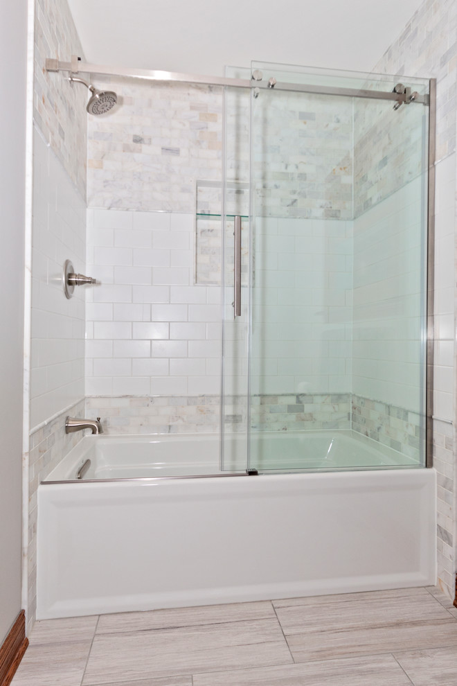 Inspiration for a mid-sized traditional master bathroom in Chicago with furniture-like cabinets, dark wood cabinets, an alcove tub, a shower/bathtub combo, a two-piece toilet, white tile, marble, grey walls, ceramic floors, an undermount sink, engineered quartz benchtops, beige floor, a sliding shower screen and beige benchtops.