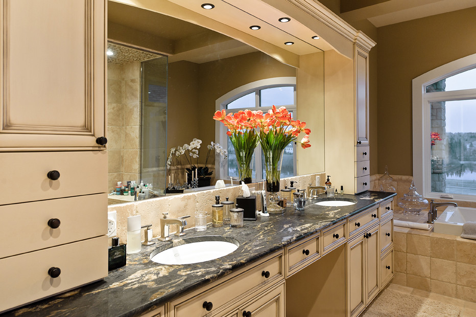 Inspiration for a large arts and crafts master bathroom in Edmonton with recessed-panel cabinets, beige cabinets, a drop-in tub, a two-piece toilet, beige tile, stone tile, beige walls, travertine floors, an undermount sink and solid surface benchtops.