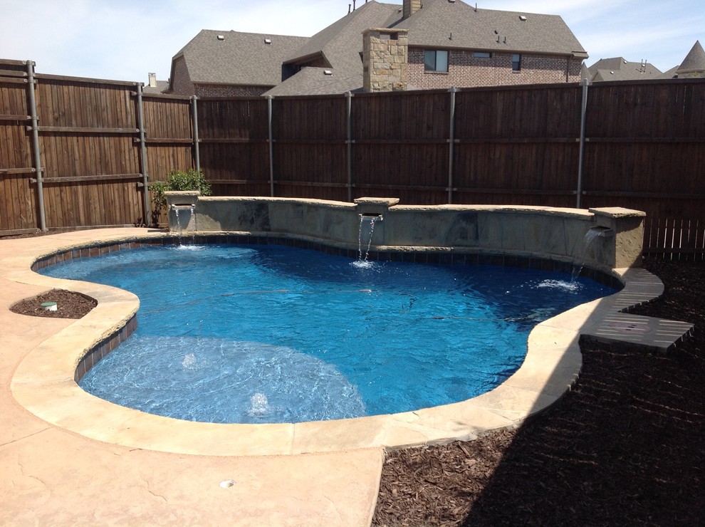 Inspiration for a mid-sized transitional backyard custom-shaped pool in Dallas with a water feature and stamped concrete.