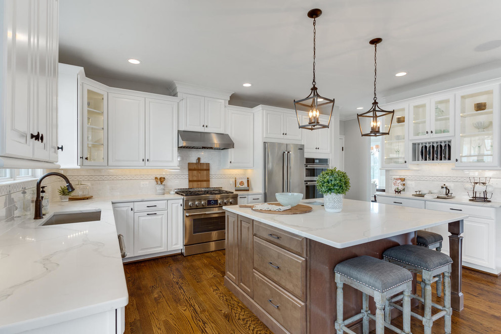 Photo of a traditional kitchen in DC Metro with an undermount sink, white cabinets, multi-coloured splashback, stainless steel appliances, medium hardwood floors, with island and raised-panel cabinets.
